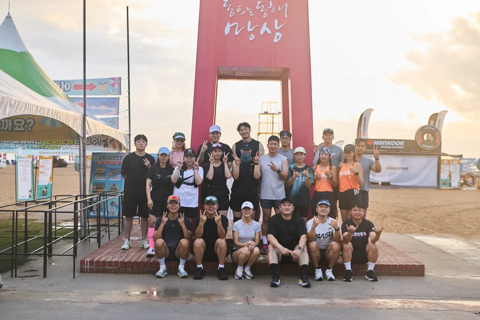 망상 시계탑 앞에서 정면을 바라보며 웃는 러닝 참가자들의 단체사진